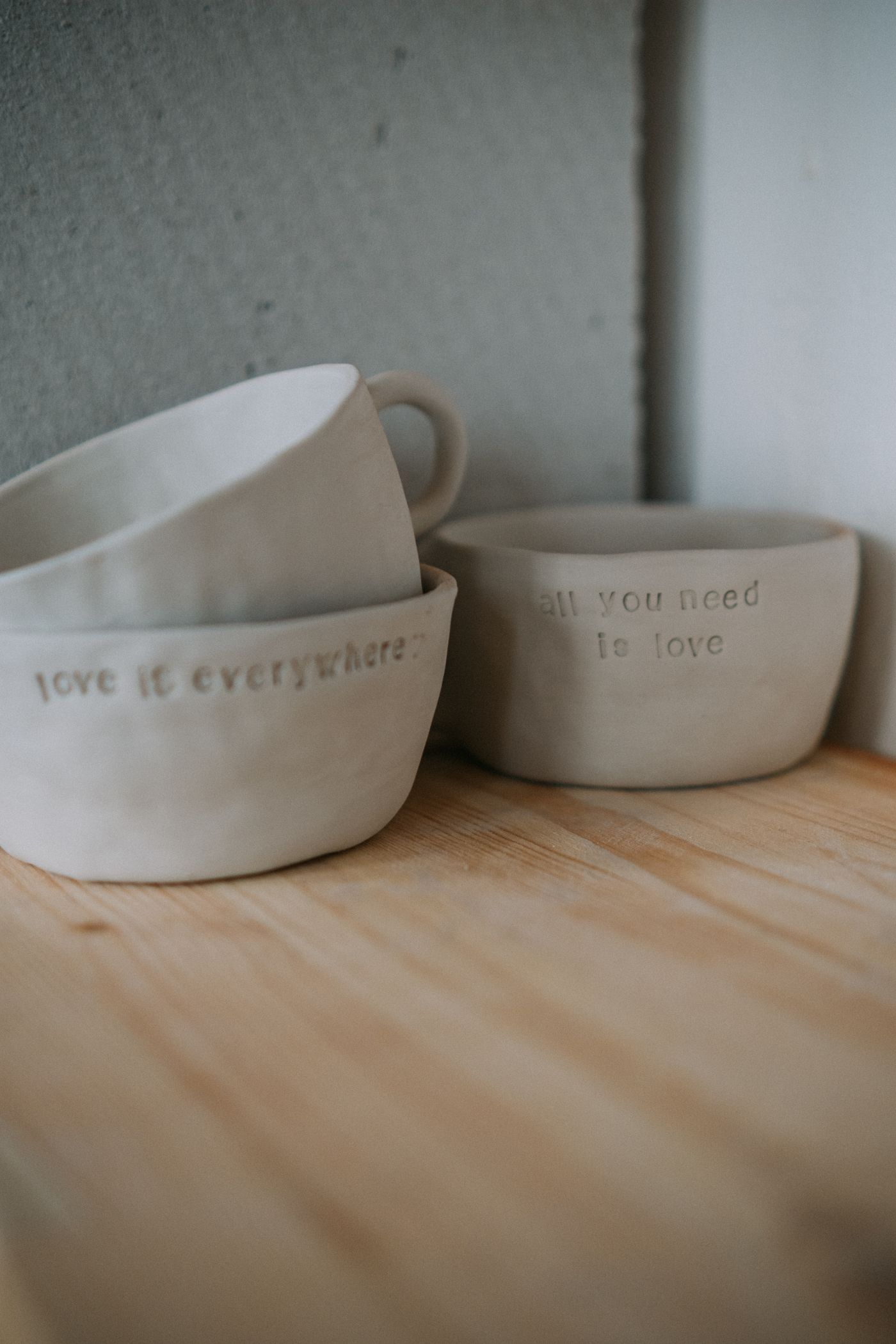 Handmade ceramic mugs and small bowls on wood