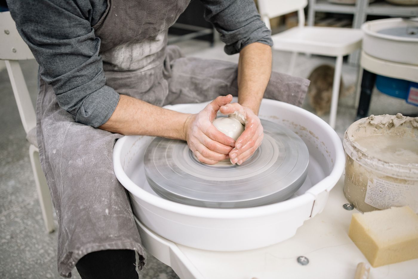Hands shaping a clay pot on the wheel